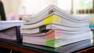 A stack of paperwork bundled together with different coloured corner clips